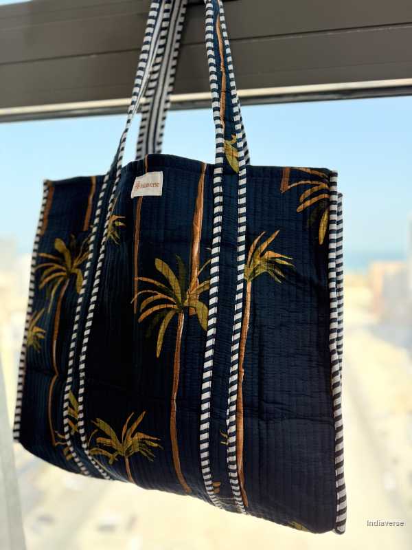 Navy blue tote bag with palm tree design on a beach