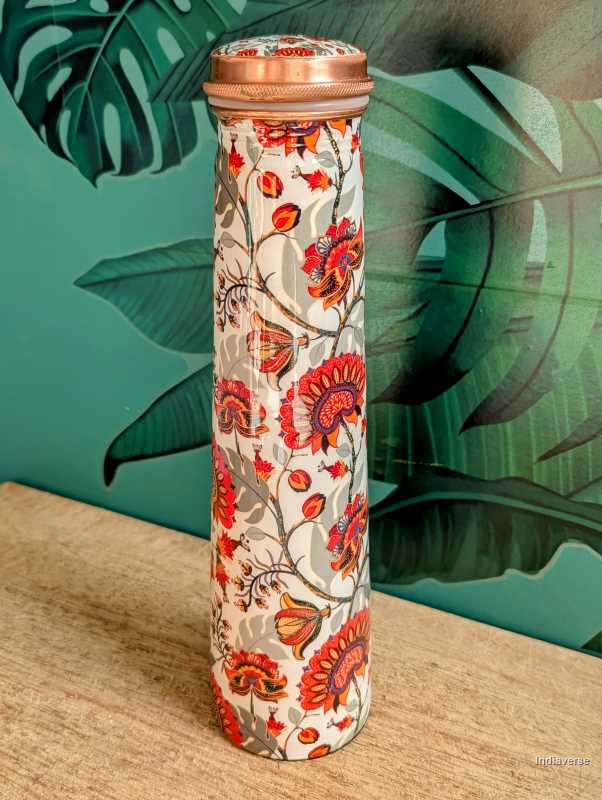 Tower shaped copper bottle with enameled red and grey floral design on a white base for carrying water with a capacity of 700 ml