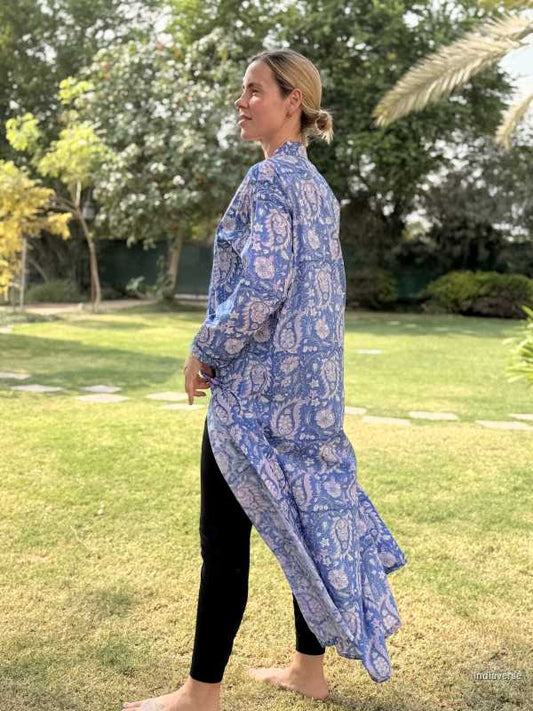 Woman wearing a blue floral dress standing on grass with trees in the background