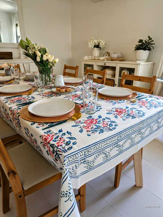 Dining room with a table set for a meal, featuring a floral tablecloth.