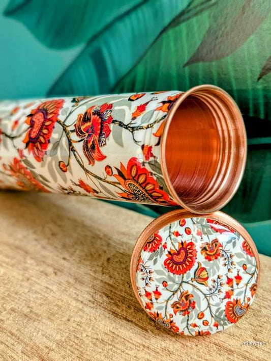 Tower shaped copper bottle with enameled red and grey floral design on a white base for carrying water with a capacity of 700 ml
