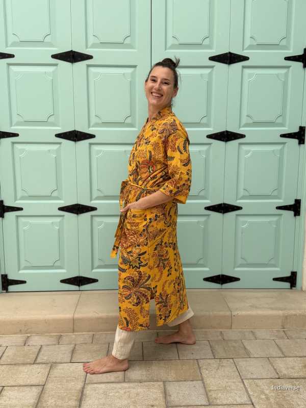 Woman wearing a yellow waffle cotton bathrobe with floral print, standing barefoot in front of a mint green door