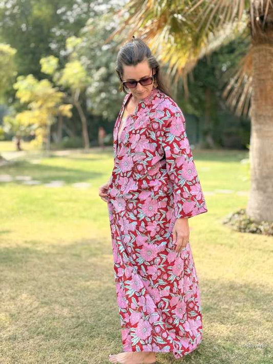 Woman wearing a pink floral dress standing in a park.