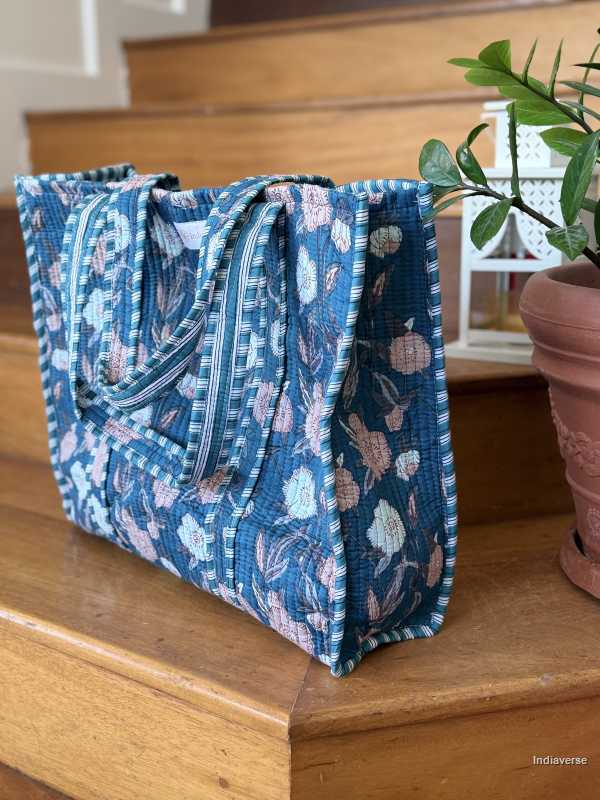 beautiful hand block printed quilted cotton tote bag with pink and off white floral design perfect tot carry all your essentials sitting on wooden staircase side view