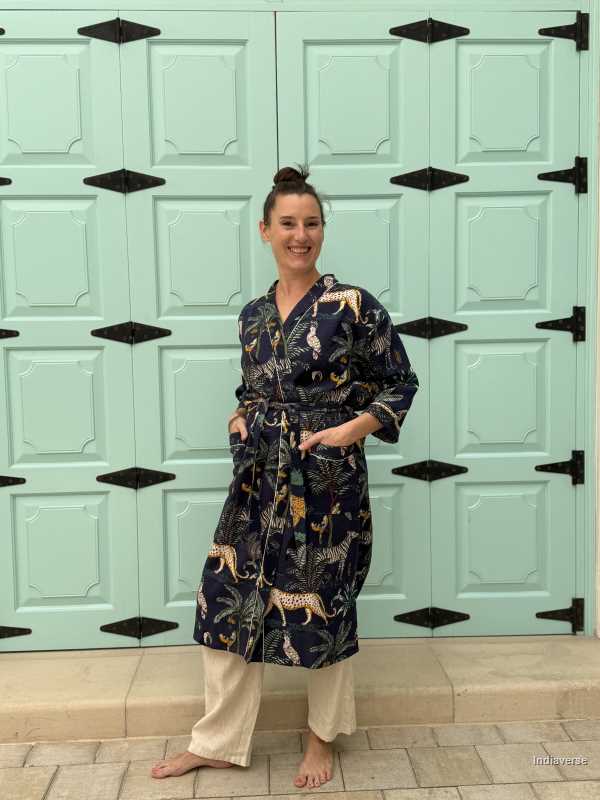Woman wearing a dark blue waffle cotton bathrobe with jungle animals and tropical motifs, smiling and posing casually