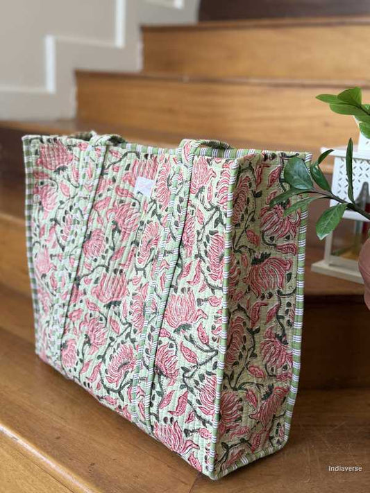 Quilted cotton tote bag in melon hue with red floral design sitting on wooden staircase with plants in background | Spring Queen