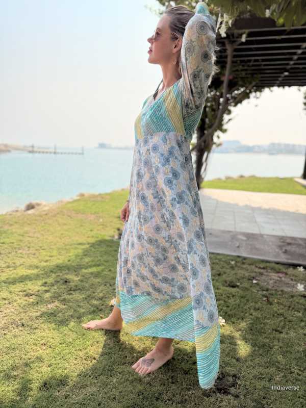 Woman in a floral dress standing on grass with a scenic background