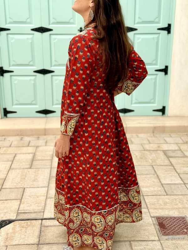 Woman wearing a full length and full sleeve maroon red wrap dress and silver detailing and paisley design trim