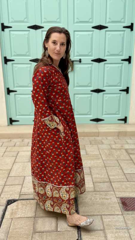 Woman wearing a full length and full sleeve maroon red wrap dress and silver detailing and paisley design trim