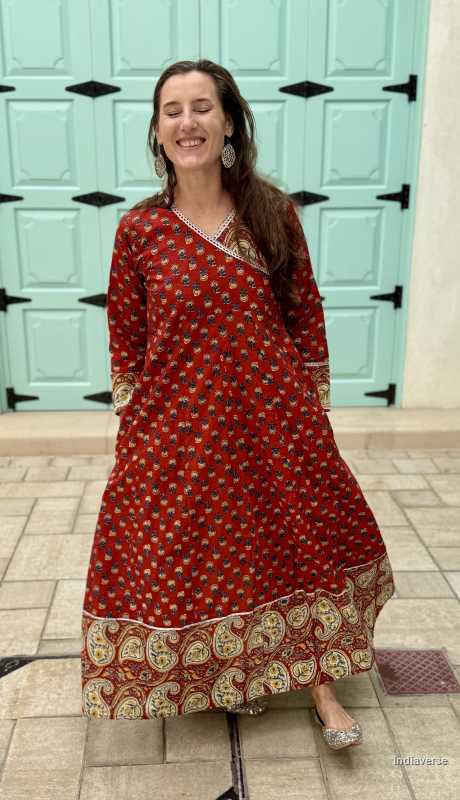 Woman wearing a full length and full sleeve maroon red wrap dress and silver detailing and paisley design trim