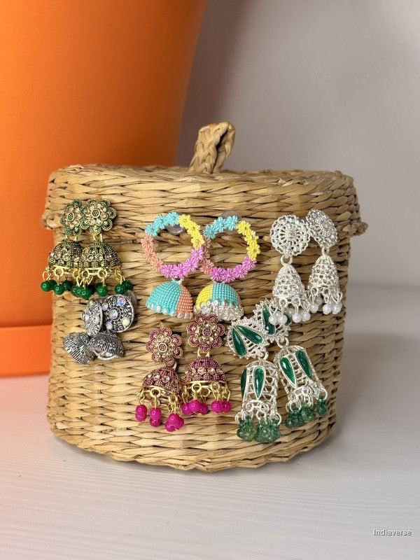 a variety of different earrings hanging from a small wicker basket