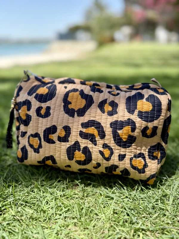 leopard print in beige and orange color toiletry pouch bag sitting on green grass