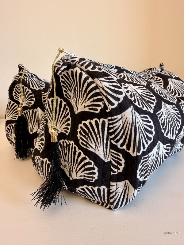 A black and white patterned fabric pouch with black tassels and gold-tone zipper pulls, photographed on a plain light background | Black Sea Shell