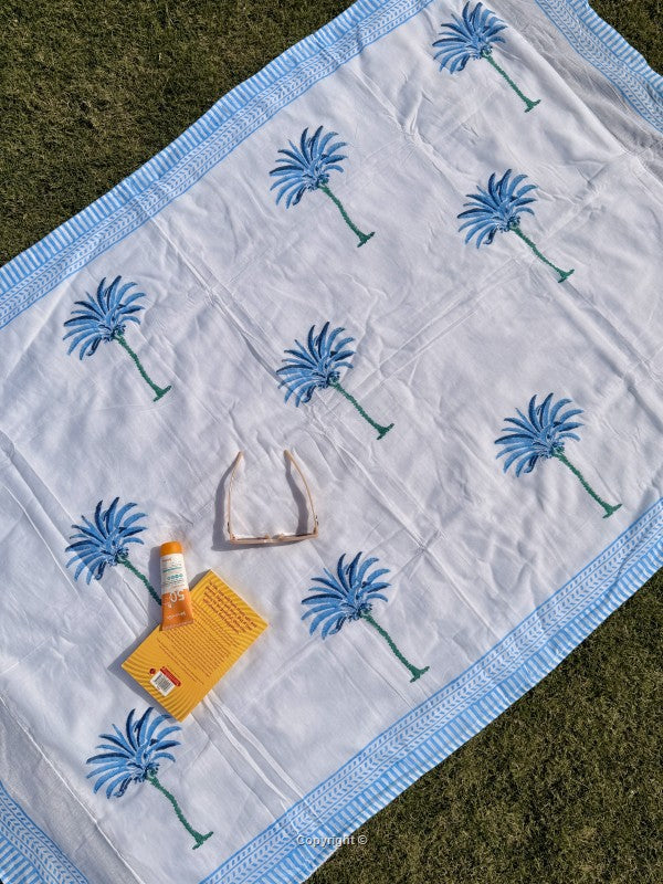 White blanket with blue floral patterns on a grassy surface