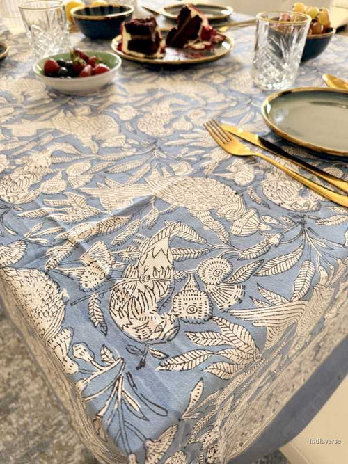 Table setting with a floral tablecloth, plates, and cutlery on a dining table.