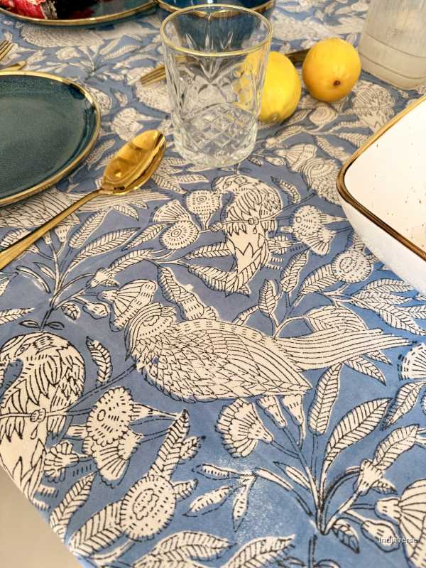 Table setting with a decorative tablecloth featuring bird and leaf patterns.