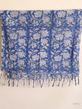 Blue cotton scarf with white floral design hanging from a wooden beam