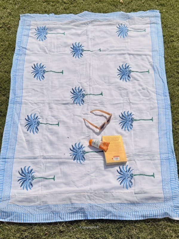 Floral-patterned quilt on grass with a bottle and box on top