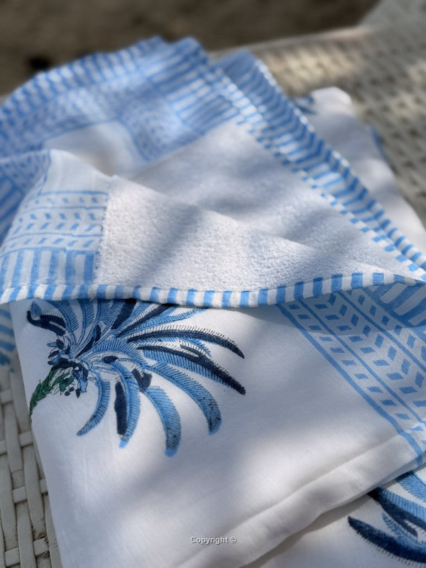 White towel with blue patterns and embroidery on a woven surface