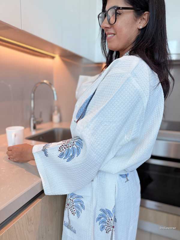 Woman in a light blue embroidered dress standing in a kitchen.