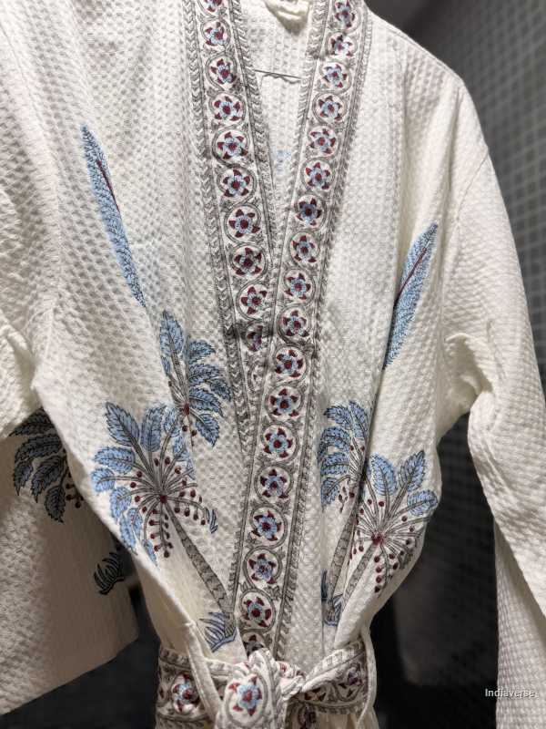 White garment with intricate blue and purple embroidery on a plain background
