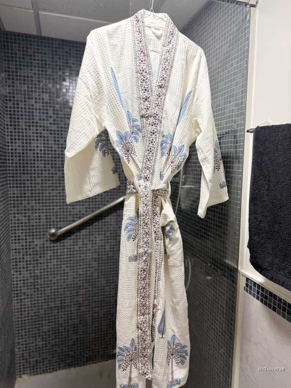 Embroidered robe hanging in a bathroom with black tiled walls.