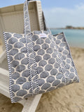 quilted tote bag with sea shell design hanging from a beach chair