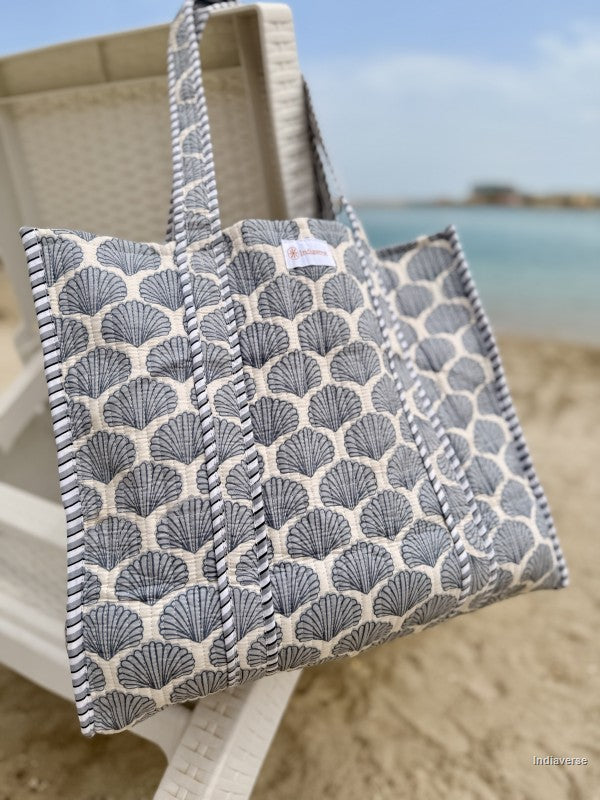 quilted tote bag with sea shell design hanging from a beach chair
