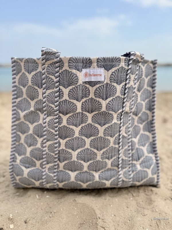 light blue sea shells print on a tote bag sitting in the sand