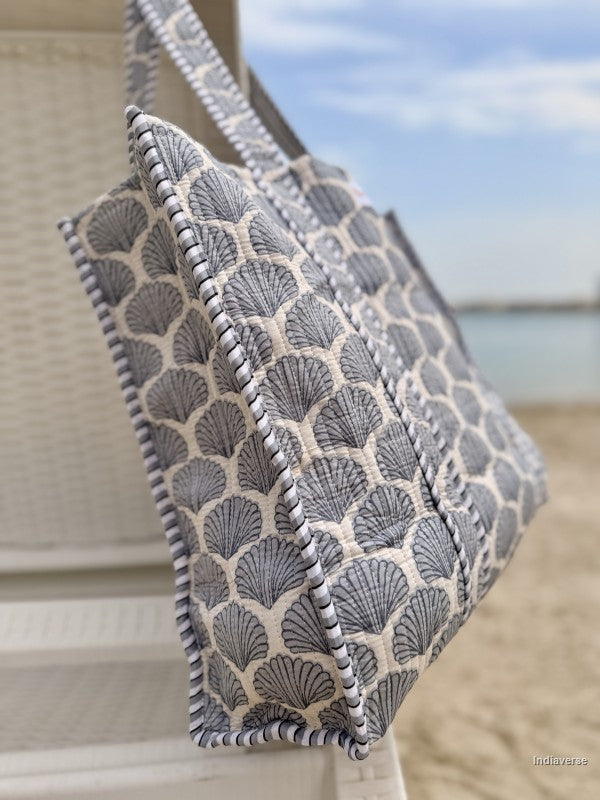 side view of tote bag with sea shell print hanging from a beach chair