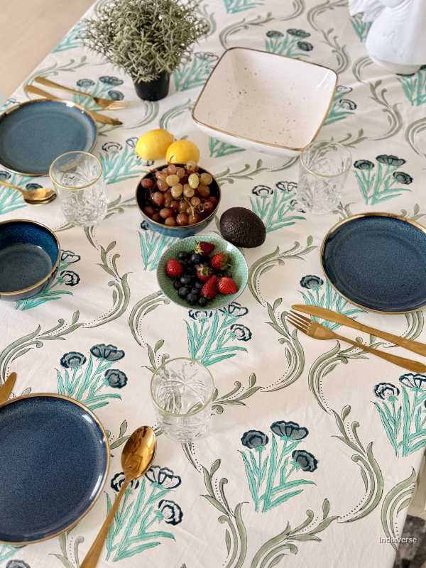 Dining table setting with floral-patterned tablecloth, plates, and cutlery.