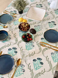 Dining table setting with floral-patterned tablecloth, plates, and cutlery.