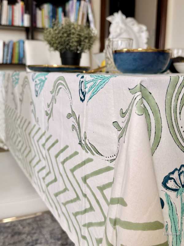 Tablecloth with green and white pattern on a table in a room with books and decor.