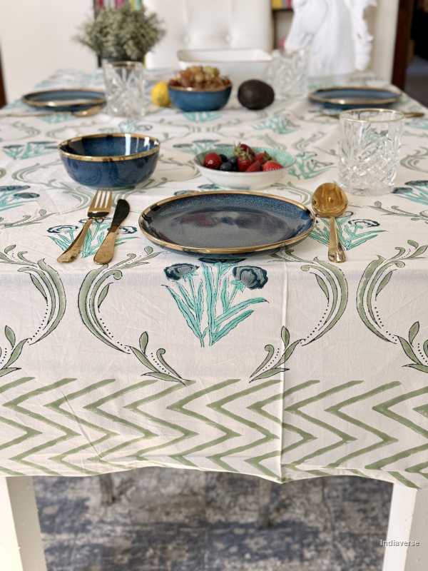 Table setting with a decorative tablecloth featuring green patterns.