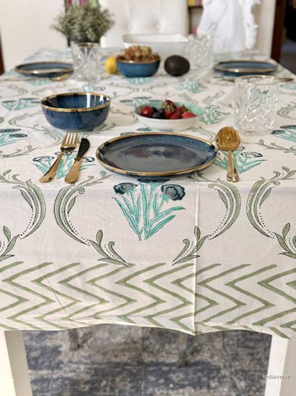 Table setting with a decorative tablecloth featuring green patterns.