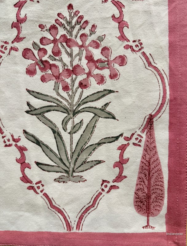 A close-up of a textile or fabric print featuring a botanical design with pink flowers, muted green leaves, and a pink border on an off-white background.
