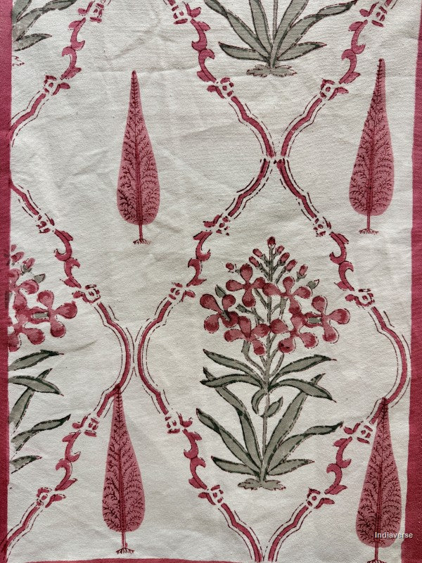 A close-up of a textile or wallpaper pattern featuring a cream background with a repeating damask-style lattice design in dusty rose and olive green, decorated with floral and leaf motifs.