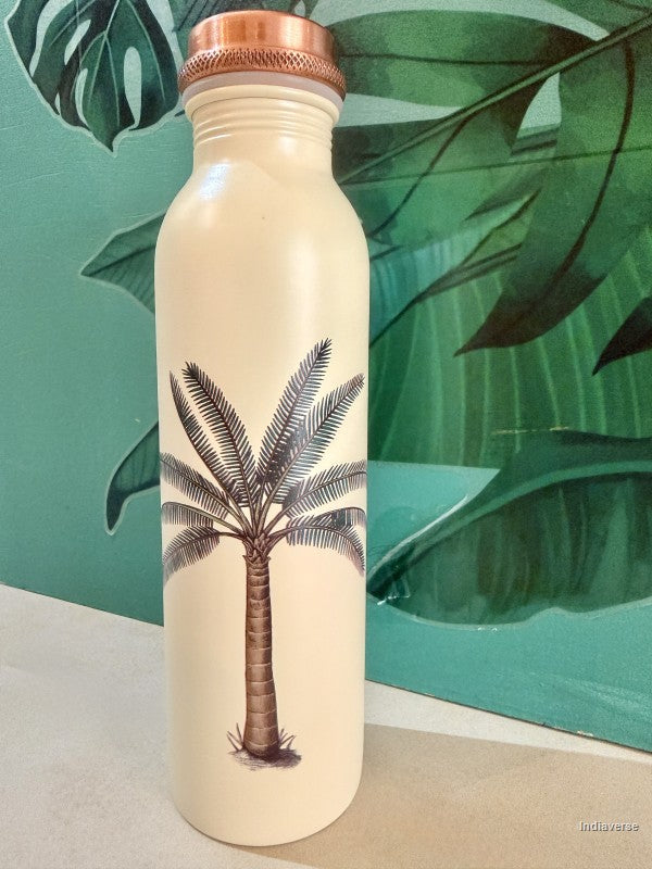 beige copper water bottle with single palm tree design standing in front of a green leaf wallpaper