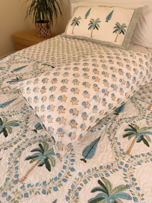 Cotton comforter on a queen size bed with blue and green palm tree design on a white background with two matching pillow cases