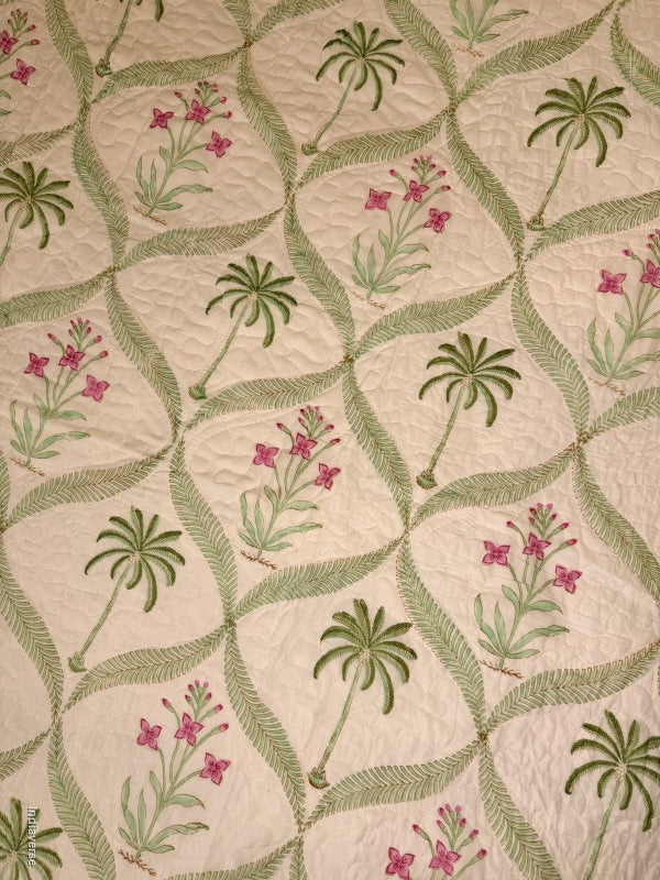 Cotton comforter with two matching pillow cases and floral and palm tree design arranged in arabesques on a queen size bed