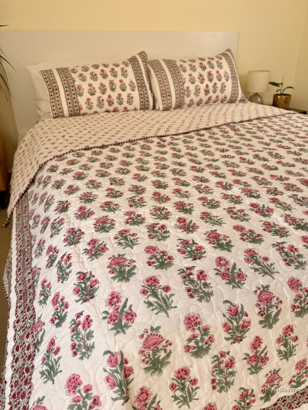 Cotton comforter with red floral design neatly arranged with matching pillow cases in a queen size bed