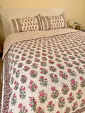 Cotton comforter with red floral design neatly arranged with matching pillow cases in a queen size bed