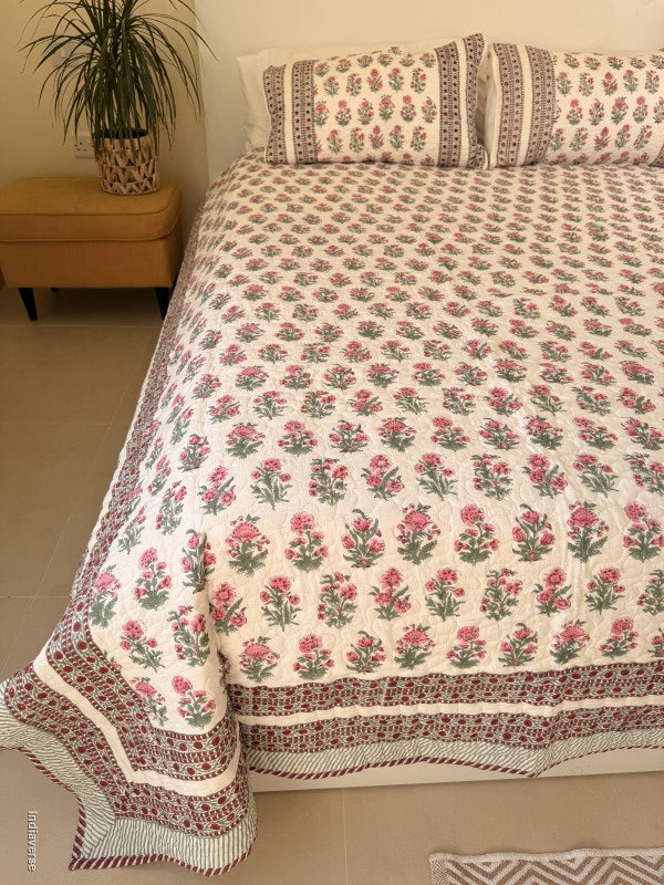 Cotton comforter with red floral design neatly arranged with matching pillow cases in a queen size bed