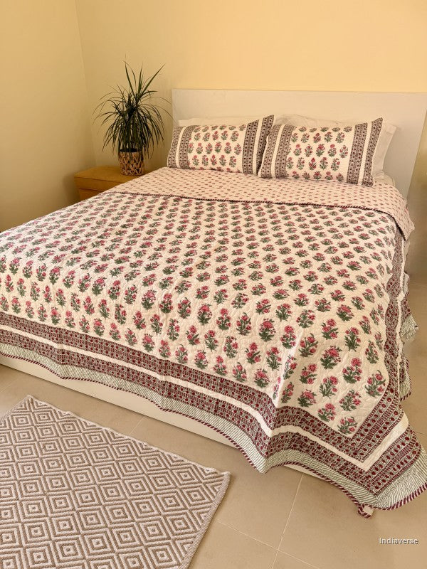 Cotton comforter with red floral design neatly arranged with matching pillow cases in a queen size bed