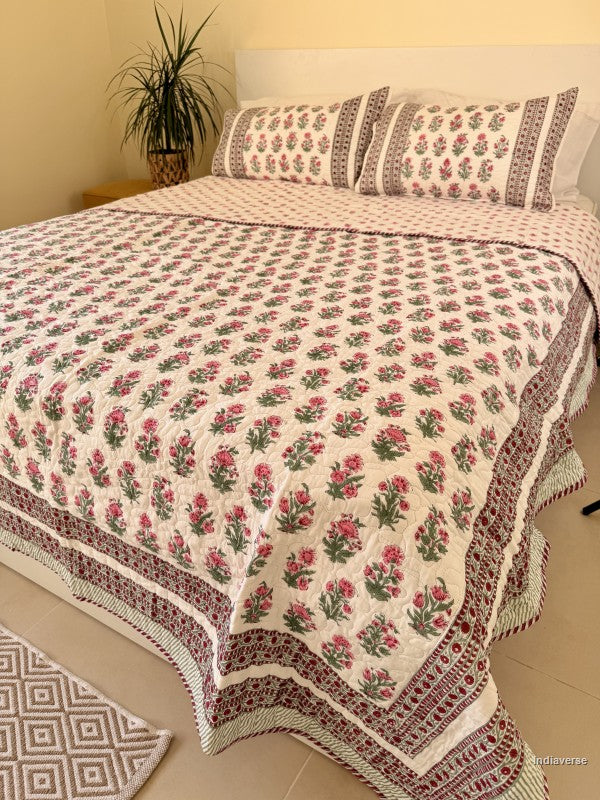 Cotton comforter with red floral design neatly arranged with matching pillow cases in a queen size bed