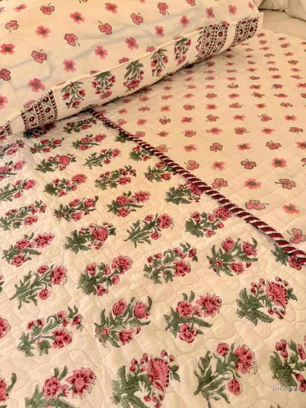 Close up of the pillow case and cotton comforter with red floral design neatly arranged with matching pillow cases in a queen size bed
