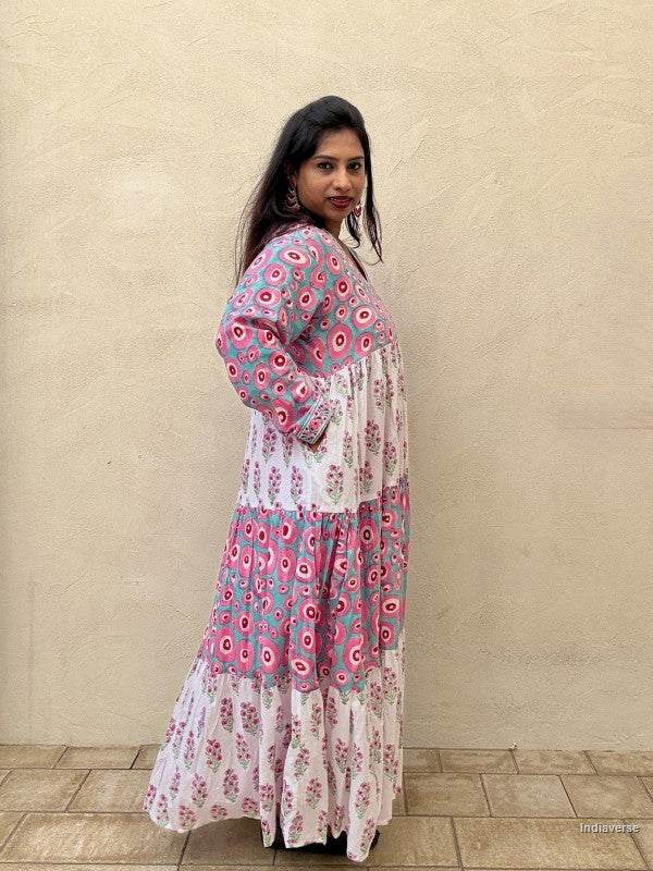 Woman wearing a long cotton dress with circle design and small geometrical floral print standing against a beige wall