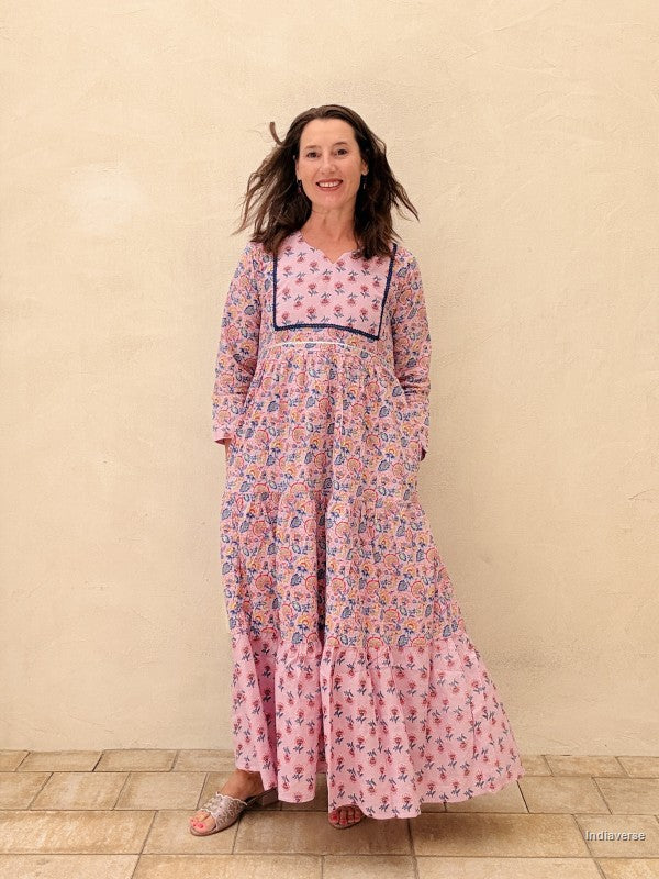 Woman wearing a pink floral dress standing against a beige wall.