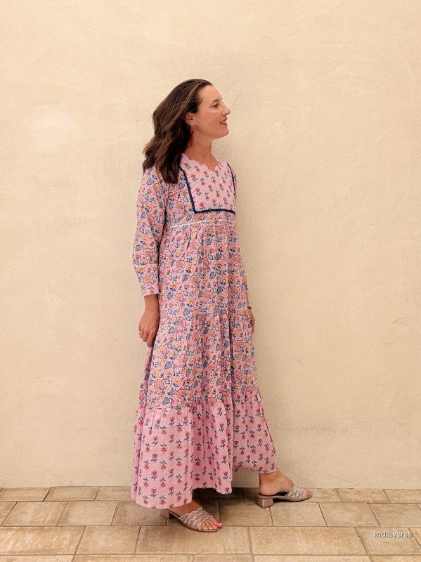 Woman wearing a pink floral dress against a beige wall.