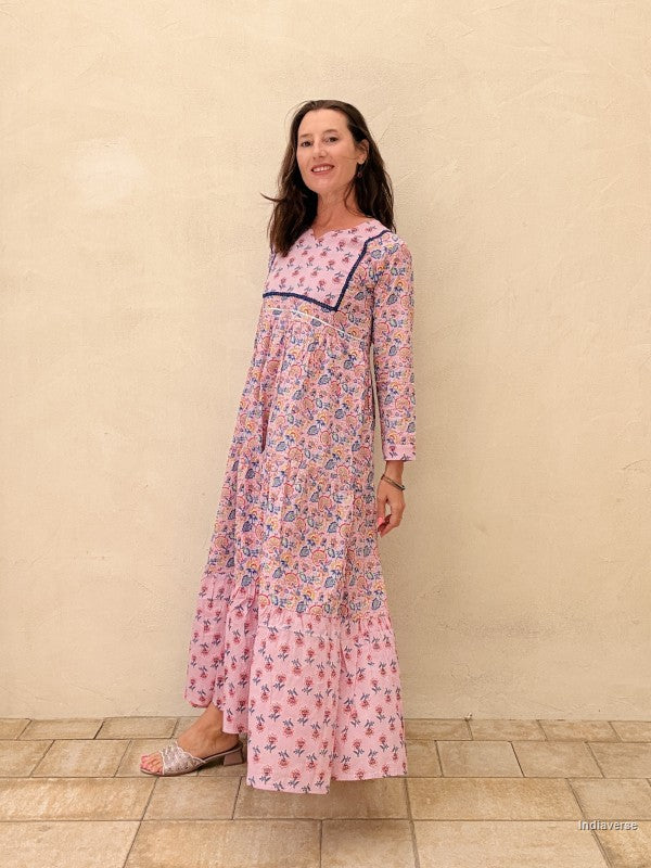 Woman wearing a pink floral dress standing against a beige wall.
